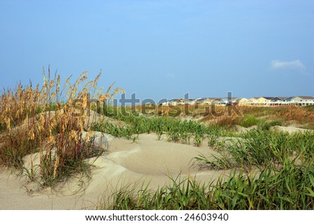 Color DSLR image of luxury vacation beach houses seen across the green grass covered sand dunes, Sunset Beach, North Carolina. Horizontal orientation with copy space for text.