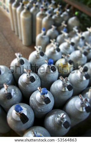 metal scuba diving tanks in dive shop packed close together, shot with narrow depth of field on a full tanks valve