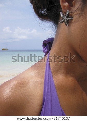 close-up of starfish earing being worn by asian female on beach with sea over her shoulder on koh tao in the gulf of thailand