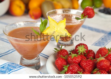 Two decorated strawberry smoothies on a vintage tablecloth