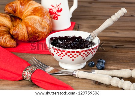 Wooden table with croissants, red napkins and antique silver napkin ring