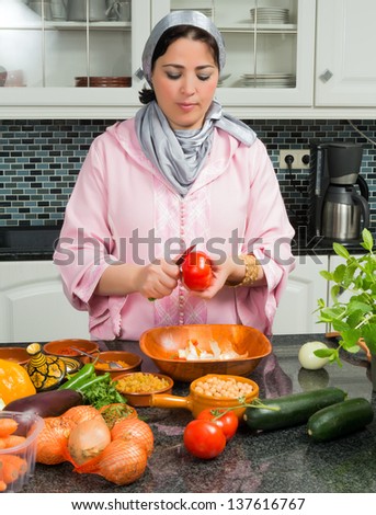 Young Moroccan immigrant woman in Europe cooking tajine during Ramadan in her modern kitchen