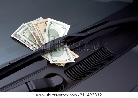 Car expenses symbolized by dollars on a windscreen wiper