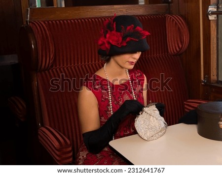 Attractive 1920s woman  in red flapper dress and cloche hat posing in the 1927 first class interior of an authentic steam train Foto stock © 