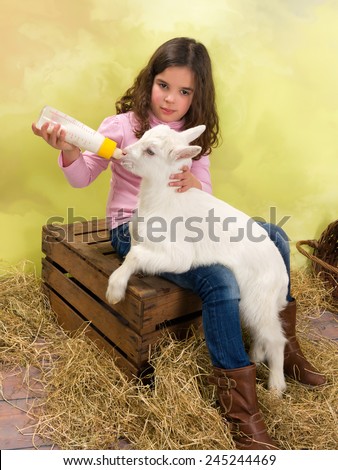 Lovely girl feeding a newborn baby goat with a milk bottle