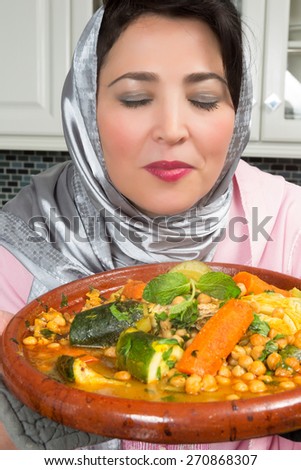 Moroccan immigrant woman in Europe presenting her tajine dish during Ramadan in her modern kitchen
