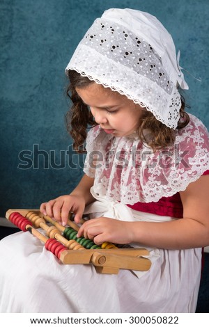Sweet victorian girl posing in the old style with an abacus