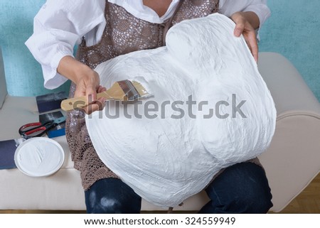 Woman painting a pregnancy belly cast with white primer, to enable decorating