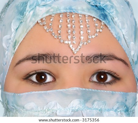 Beautiful young woman with mysterious eyes, wearing a blue silk veil