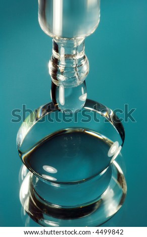 Extreme macro photo of a contact lens and an eye dropper dropping cleansing fluid into the lens