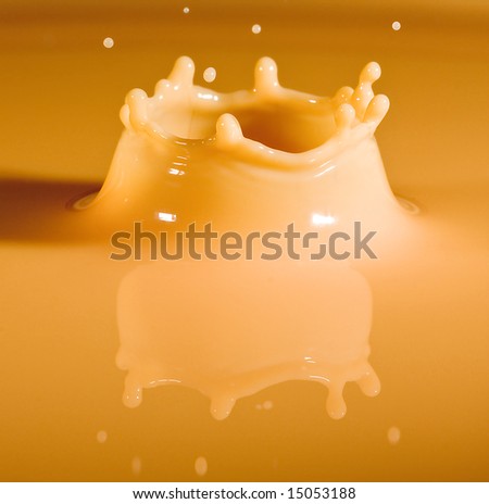 Yellow milk droplet falling into a puddle of milk