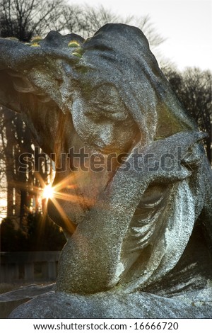Tombstone statue at sunrise, with an antique mourning woman in stone