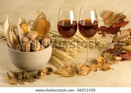 Red wine in an autumn decor with leaves, corncobs and walnuts