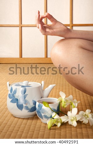 Meditating woman on japanese tatami mat with orchids and green tea
