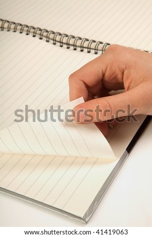 Female hand turning a page of an empty notebook