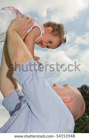 Older father holding his little girl high in the sky