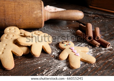Rolling pin and homemade gingerbread men biscuits on a wooden board with flour