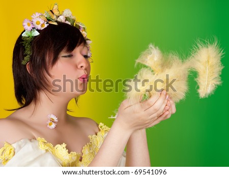 Springtime girl with butterfly and flower hair blowing easter feathers