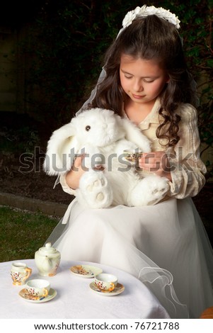 Little Alice in Wonderland girl drinking tea with a white rabbit