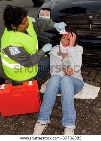 Female paramedic attending to a young car crash victim (the sleeve badges have been replaced by a non existing logo)