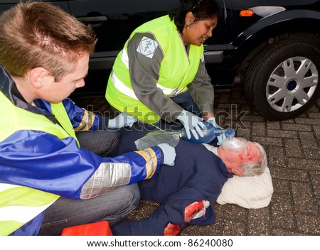 Paramedics helping a car crash victim with an oxygen mask (sleeve badges have been replaced by a non exisiting logo)