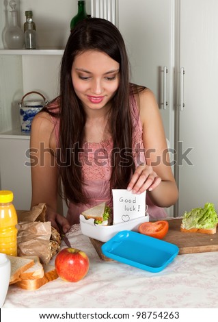 Young woman putting a good luck note in a lunchbox