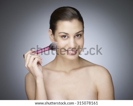 Shot of a beautiful young woman applying blush with a makeup brush