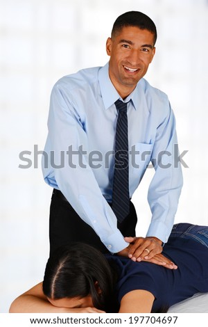 Male chiropractor working at his office with a patient