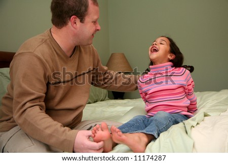 Dad tickles his daughter before she goes to bed