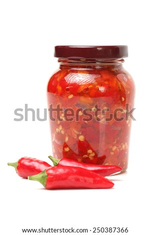 Fresh red chilly and bottled chili sauce over white background