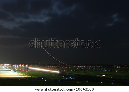 long time exposure of an aircraft taking off  with the back light forming a curve into the sky