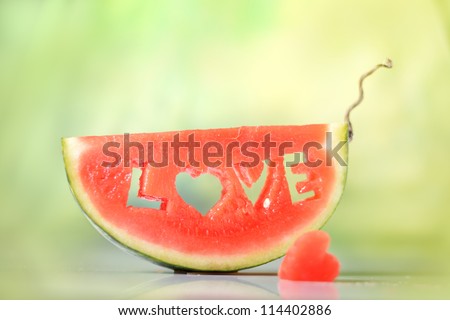 Fresh juicy watermelon slice on natural green background close-up with love letters word