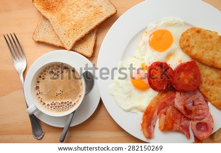 A set of traditional English breakfast, Plate with fried eggs, bacon and hash-brown, toast and coffee on wooden table
