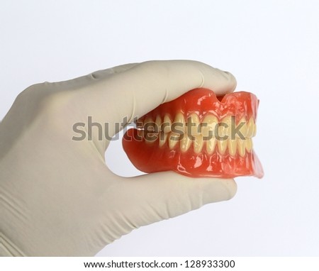 Hand holding Denture / Prosthesis / Dental / Teeth / Denture isolated on white
