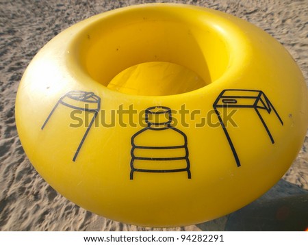 Trash can for recycling of plastic in yellow color on beach / Barcelona, Spain