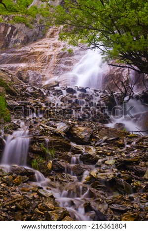Beautiful waterfall flowing among stones, rocks and forest in the Altai mountains, Russia.