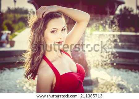 young beautiful brunette girl near water fountain in a hot day