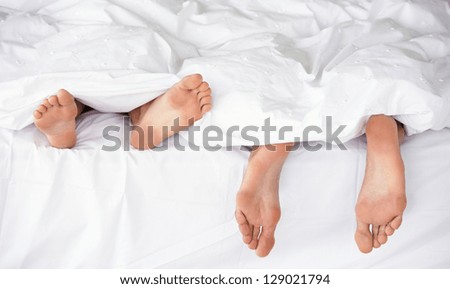 Closeup of a couple\'s feet in bed sleeping