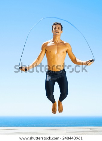 Young man on the beach is jumping rope
