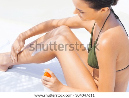 Attractive Woman In Bikini Sitting At Beach With Sun Protection Cream