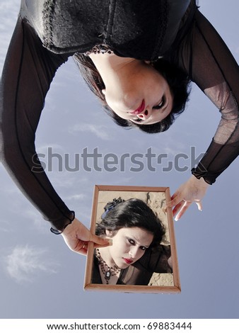 Young woman looking at viewer through a mirror over her head