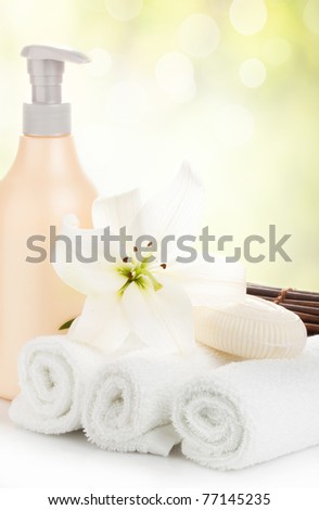 Flower and soap on soft white towels against abstract nature background (spa, hotel, relaxation, bathing concept and more)