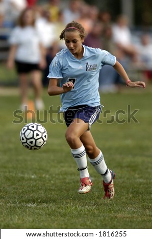 high school girl soccer player runs with eye on the soccer ball
