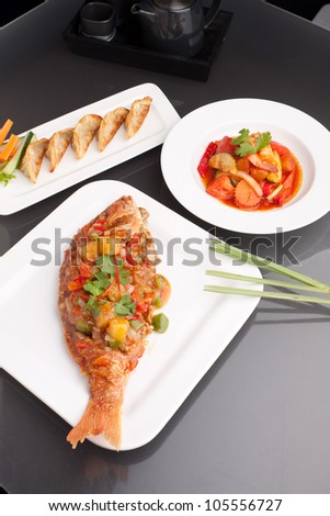 Freshly prepared Thai style whole fish red snapper dinner with sweet and sour shrimp and pan fried gyoza dumplings appetizer.