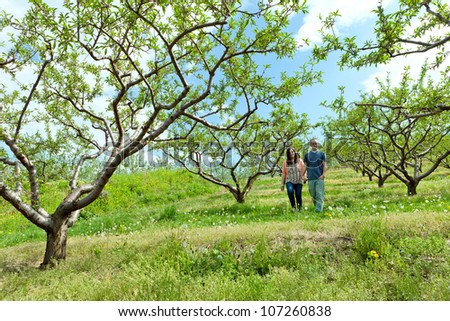 Young happy couple enjoying each others company outdoors walking through an orchard.