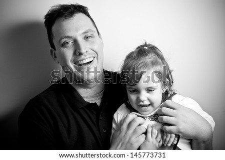 A young happy toddler aged little girl posing with her daddy. Black and white.