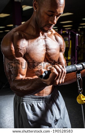 Fit male body builder working out  using a resistance weight machine.