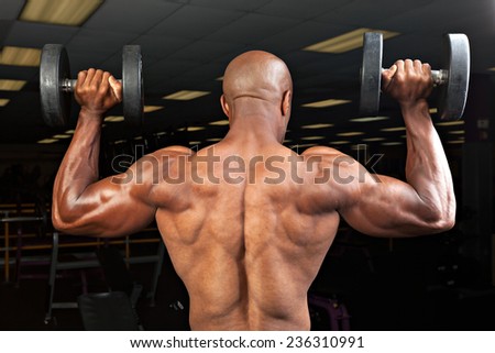 Strong back and shoulders on a  ripped lean muscle fitness man lifting weights.