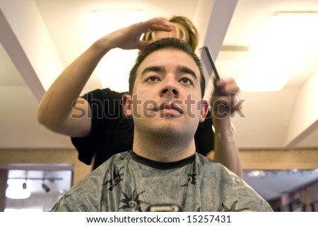 A young man getting his hair cut by a hairdresser at the salon