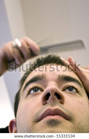 A young man getting his hair cut by a hairdresser at the salon